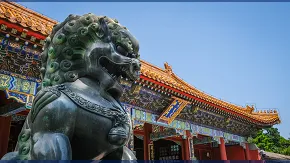 Temple en chine de couleurs vives avec en premier plan une statue d'un lion