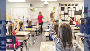 Salle de cours avec des enfants de dos levant la main